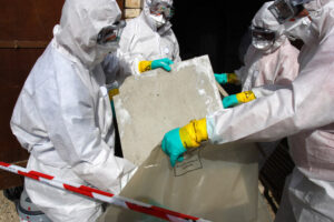 asbestos removal near me- a group of people wearing hazmat suits and goggles holding a bag